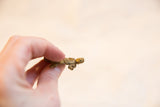 A small African bronze turtle pendant held to show its profile and handmade form.