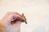 A hand holding a vintage bronze turtle pendant to show its small scale and detailed shell.
