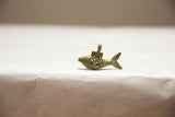 Side profile of a handmade African bronze fish pendant with an oxidized mesh body.
