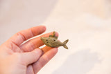 Vintage African bronze fish pendant with wire details held in hand to show its scale.