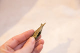 Side profile of a handmade bronze fish pendant revealing its hollow interior and oxidized finish.
