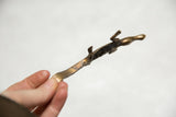 Angled profile of the vintage bronze crocodile showing its slender body and curved tail.