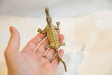 A vintage bronze crocodile figurine held to show its scale and detailed, textured back.