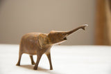 Handmade African bronze elephant figurine with trunk raised, detailed with rich patina.