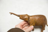 African bronze elephant figurine, rustic texture, warm patina, and raised trunk.