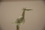 Vintage bronze stork's head showing its concentric-circle crown and textured patina.
