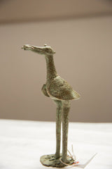 Side view of the crowned stork figure highlighting its handmade texture and oxidized bronze patina.