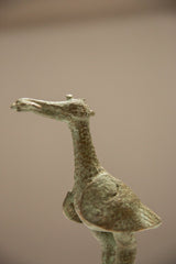 Profile detail of the vintage stork's crowned head and textured oxidized bronze surface.