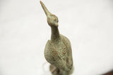 Top-down view of the vintage bronze stork's textured, oxidized surface and slender form.