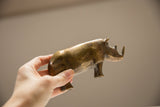 Vintage African bronze rhino held in hand, showing its rich golden patina.