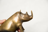 Textured golden patina bronze rhino head with horn and eye details, held by hand.