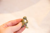 Small vintage oxidized bronze monkey, held to show handmade detail.