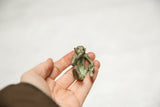 Vintage handmade bronze 'Speak No Evil' monkey with green patina, held in hand.