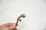 Small African bronze pangolin held in hand, showing its textured patina.