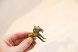 A hand holds the small vintage bronze ram, highlighting its oxidized, handmade texture.