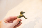 The vintage oxidized bronze ram shown in hand to illustrate its small scale.