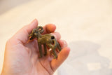 Textured vintage African bronze ram held by hand, revealing its aged patina.