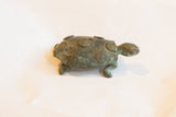 The textured, dark oxidized surface and spiral details on a vintage African turtle figurine.