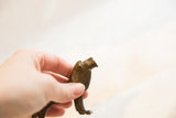 Hand holding a vintage African dark bronze lion, showing its unique handmade texture.