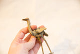 A hand holding the vintage bronze ostrich figurine to show its handmade texture and scale.