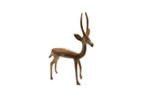 Vintage African copper gazelle sculpture with slender legs and tall horns, facing right.