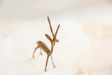 Angled view of a vintage bronze gazelle's rustic texture and straight horns.