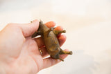 Small bronze elephant held in hand, revealing its aged, textured underside and bronze finish.