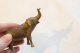 Side view of the small bronze elephant showing its speckled, handmade texture.