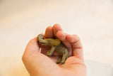 Small vintage African bronze elephant sculpture with a curled trunk, held in a hand.