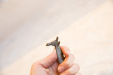 Hand holding a vintage African dark patina bronze giraffe, showing its textured neck and head.