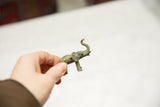 A small vintage bronze elephant with aged patina held in hand to illustrate its scale.