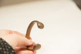 Detail of an antique African bronze bracelet's handcrafted C-shape and aged patina.