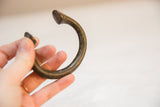 The curved shape and smooth, patinated surface of a vintage African bronze bracelet.