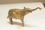 The distinct profile of a vintage golden patina elephant with its trunk held high.