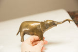 A hand holds the collectible golden elephant to show its vintage patina and scale.