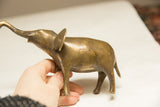 Vintage African elephant sculpture with golden patina held in hand for scale.