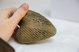 Hand holding the African bronze heart, highlighting its intricate woven mesh design.