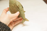 The textured mesh pattern and oxidized patina of a vintage African bronze fish.