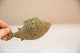 A hand holds the vintage bronze fish, highlighting its textured, spiral wire design.