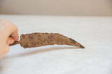Hand holding the vintage African iron chili pepper, highlighting its rustic patina.