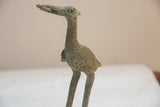 The rough, oxidized bronze texture on the neck and head of the vintage stork figure.