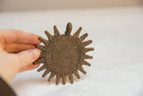 Vintage African bronze sun medallion held in hand, showing intricate coiled and ray details.