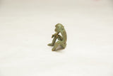 Vintage bronze monkey figurine seen in profile, highlighting its seated posture and green patina.