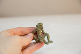 Hand holding small handmade bronze monkey with green patina.