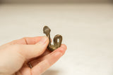 Small vintage African snake sculpture in hand, featuring aged bronze tones and handmade texture.