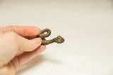 Hand holding the small, textured dark brown vintage African snake sculpture.