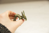 Vintage African impala sculpture held in hand, displaying its green patina and detailed eating pose.