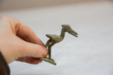Vintage African bronze stork figure with etched details held to show scale.