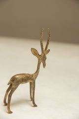 Vintage African gazelle sculpture with its head turned back, showing a light, aged patina.