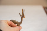 The slender horns and aged golden patina on a vintage African gazelle figurine.